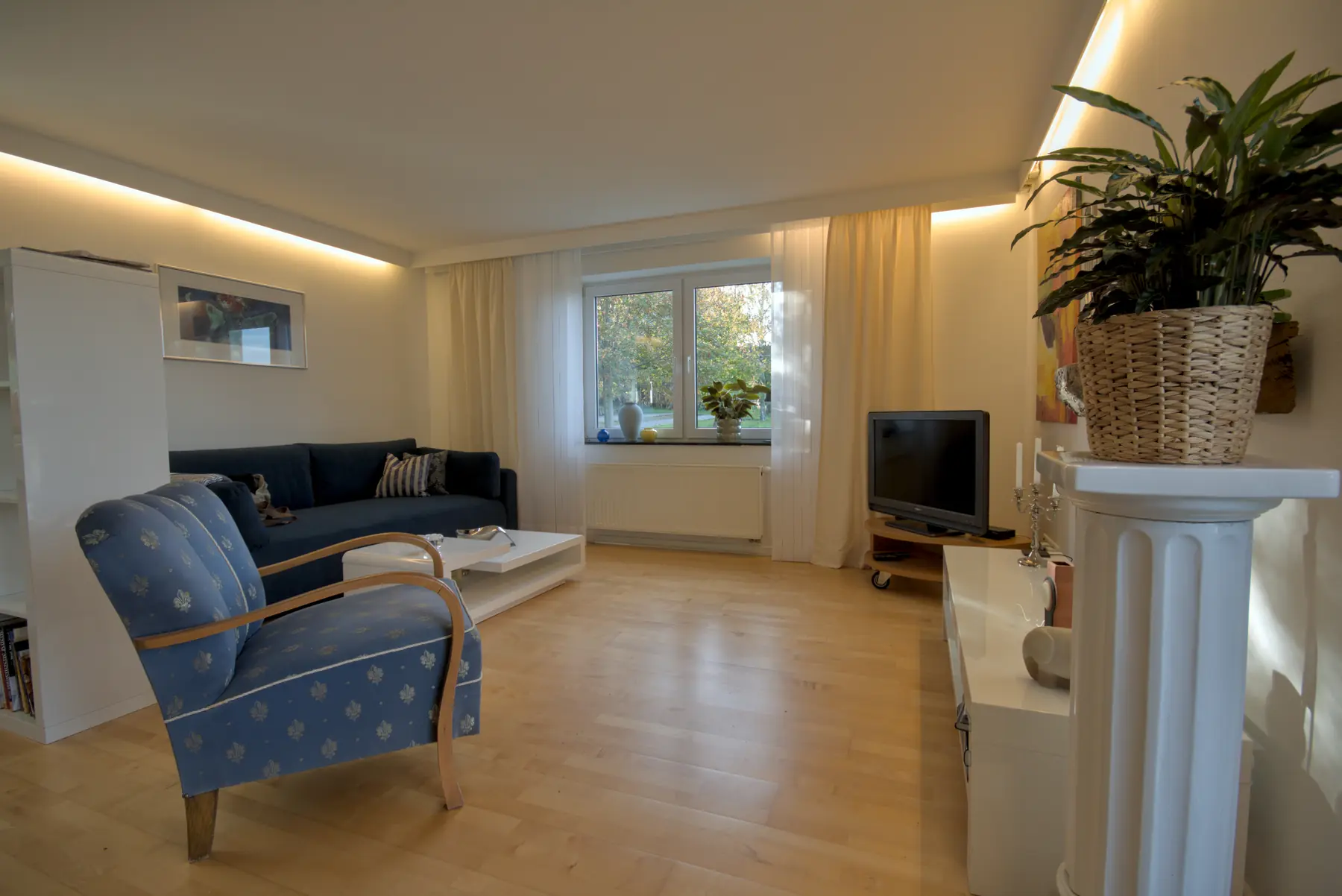 Der Wohnbereich mit Sofa, Sessel und Fenster ins Grüne